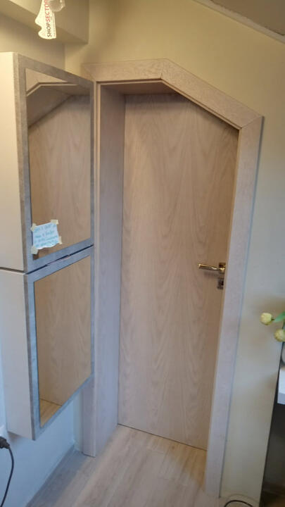 Custom angled interior door coordinated with built-in cabinetry for a sloped space